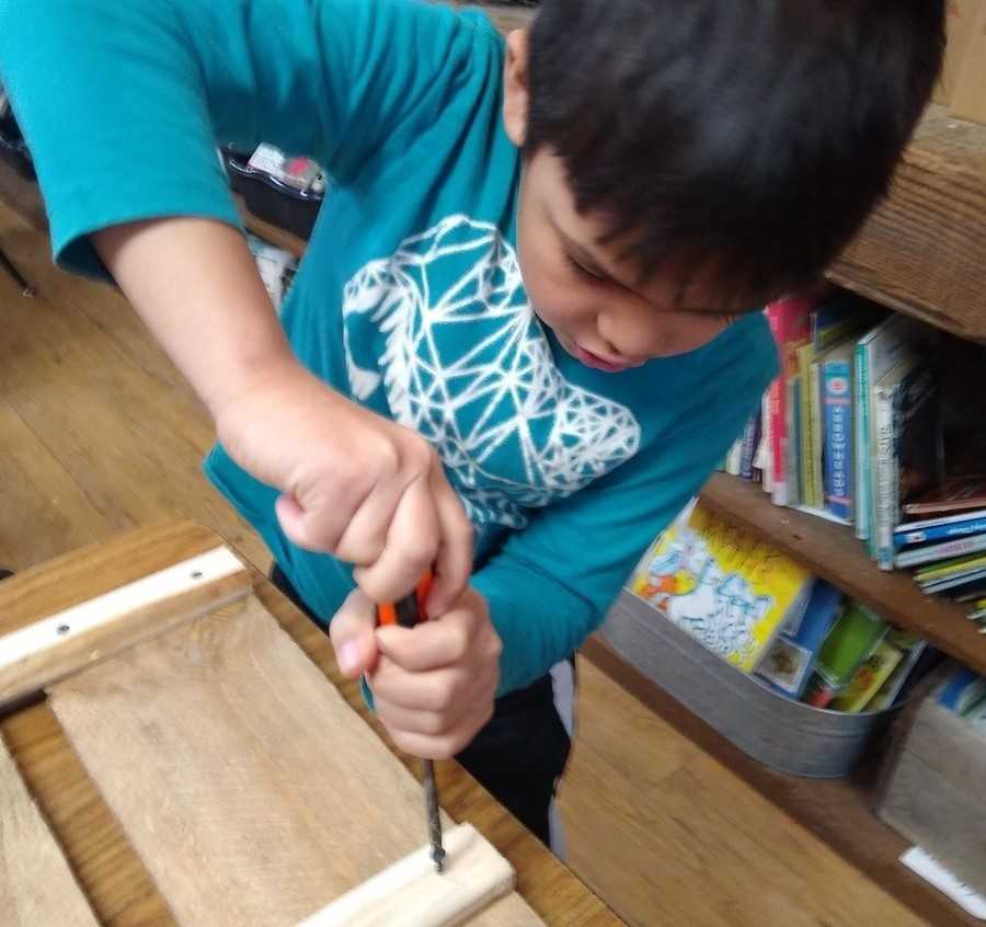 child using a screwdriver to assemble a shelf