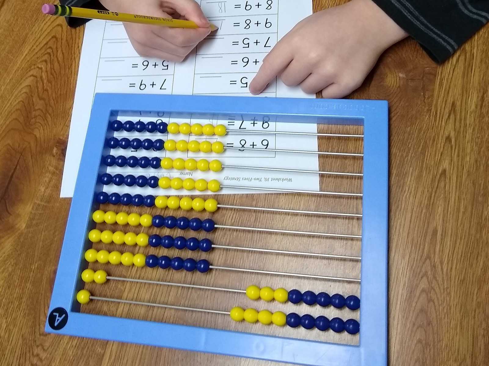 child doing math worksheet using an abacus